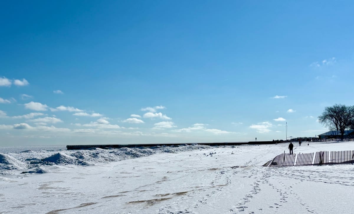 Winter beach scene on Lake Michigan. Snow and solitary figure walking.