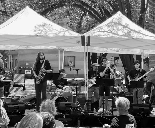 Saxophone, trombone, drums and guitar jazz musicians playing at a street fair